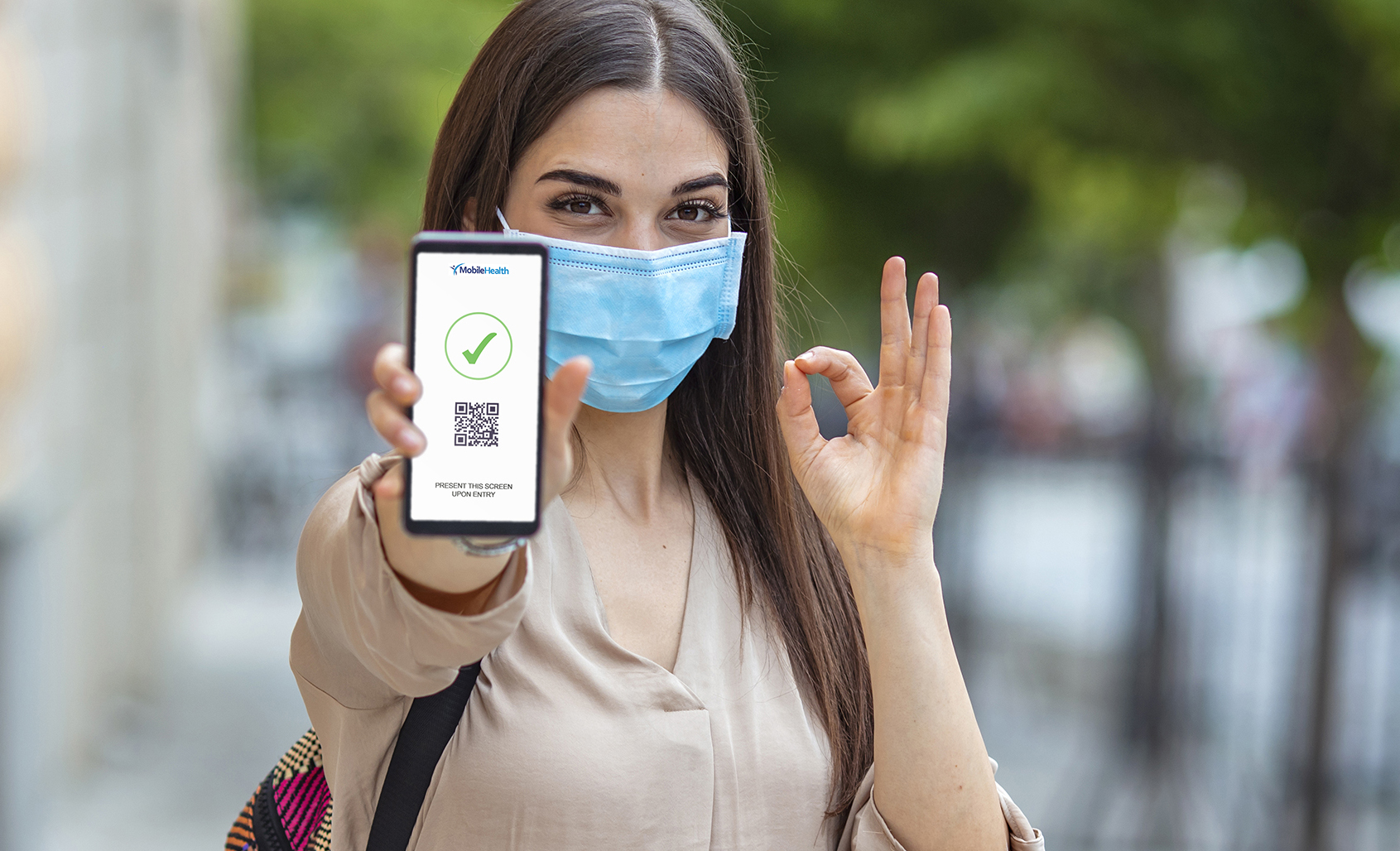 Woman wearing protective face mask and showing current air pollution on smart phone. Woman Showing Smartphone with Corona Virus App, health status related to COVID19